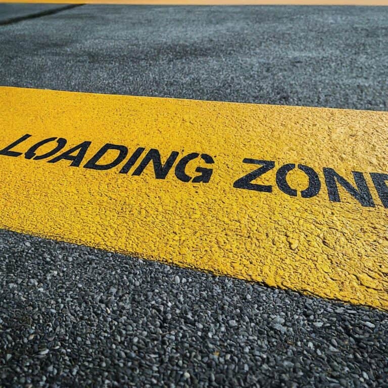 A yellow road marking on asphalt indicates a loading zone.